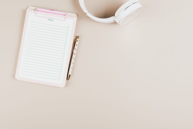 A notepad, pen and headphones arranged for planning an editing budget