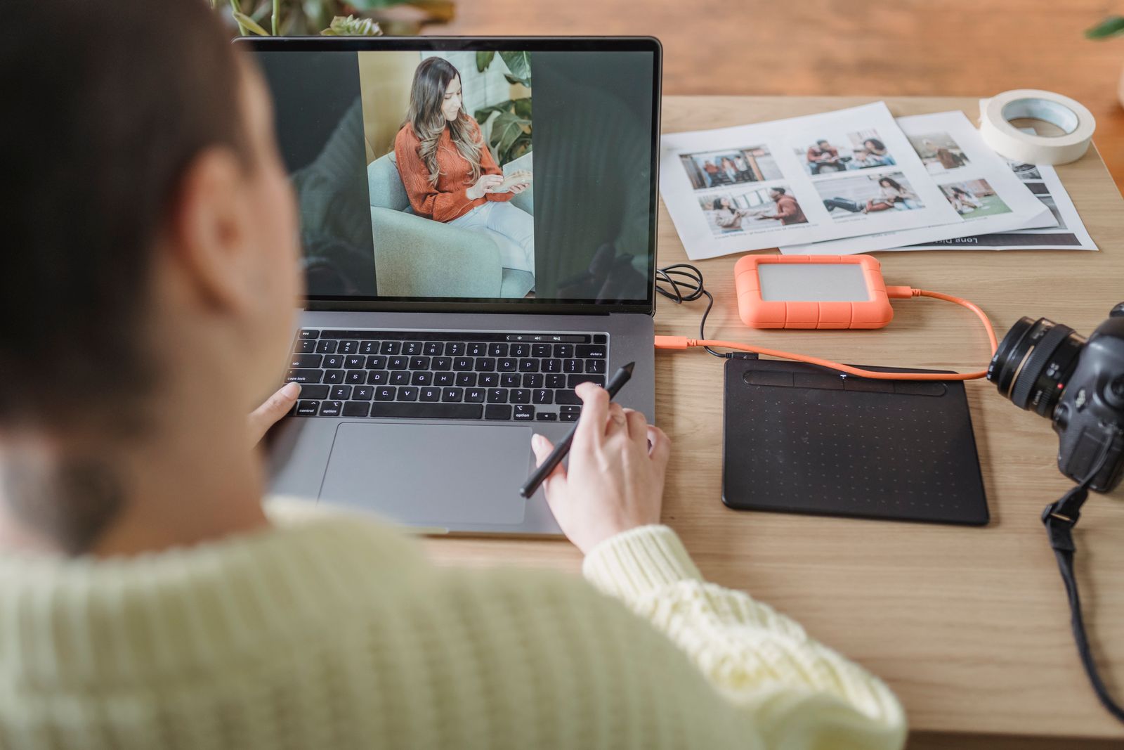 A photographer editing a photo on a laptop beside a camera and graphics tablet